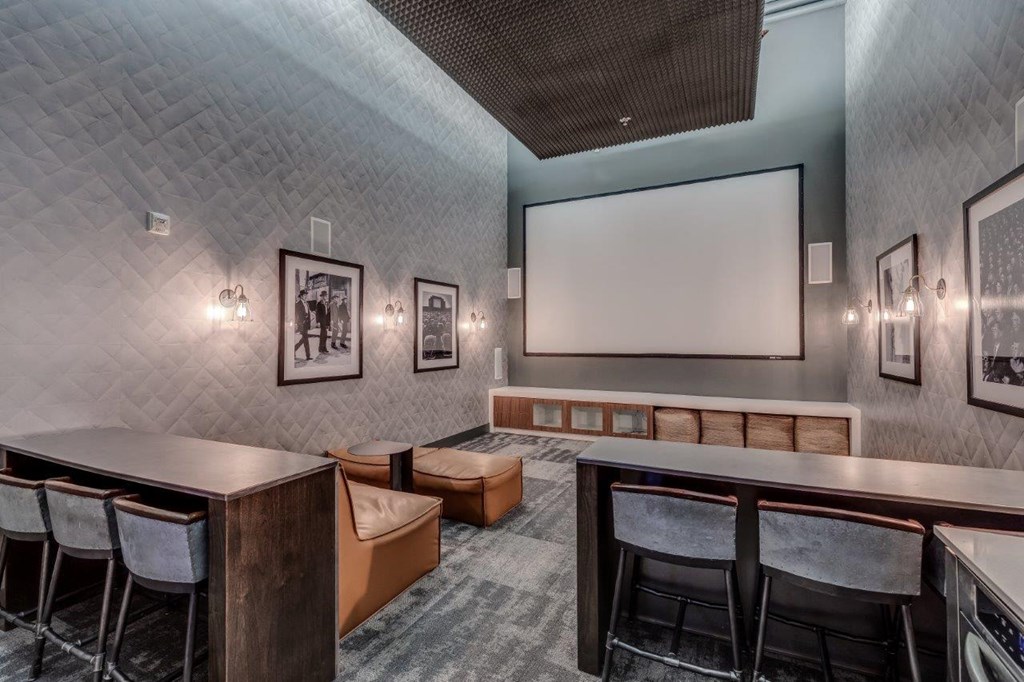 a theater room with tables and chairs and a projection screen