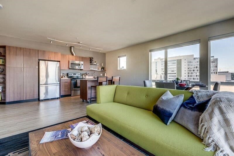 a living room with a green couch and a kitchen