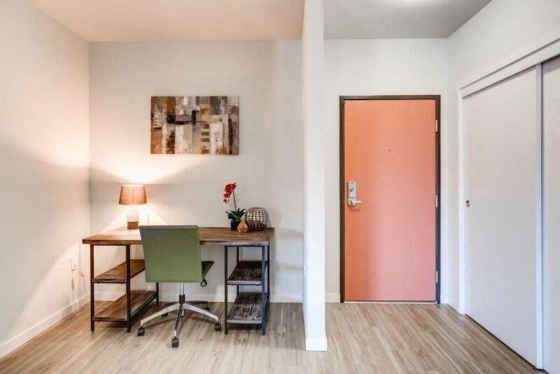 a room with a desk and a pink door