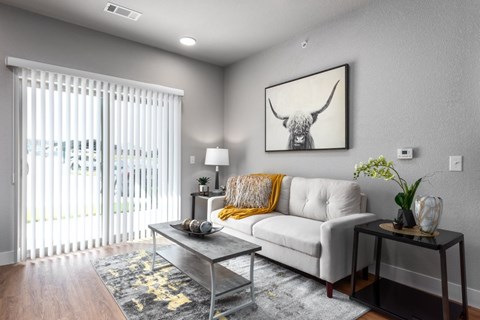A living room with a white couch, a coffee table, and a painting of a bull's head on the wall.