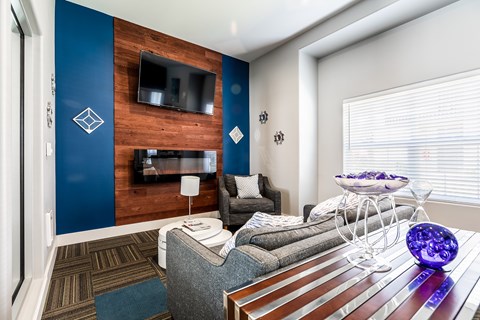 A modern living room with a grey couch and a wooden wall.