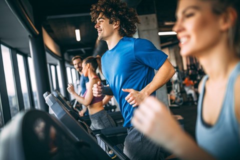 A group of people are exercising on treadmills in a gym.