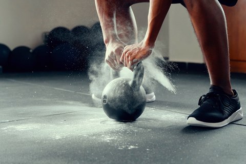 A person is throwing a kettlebell on the floor.