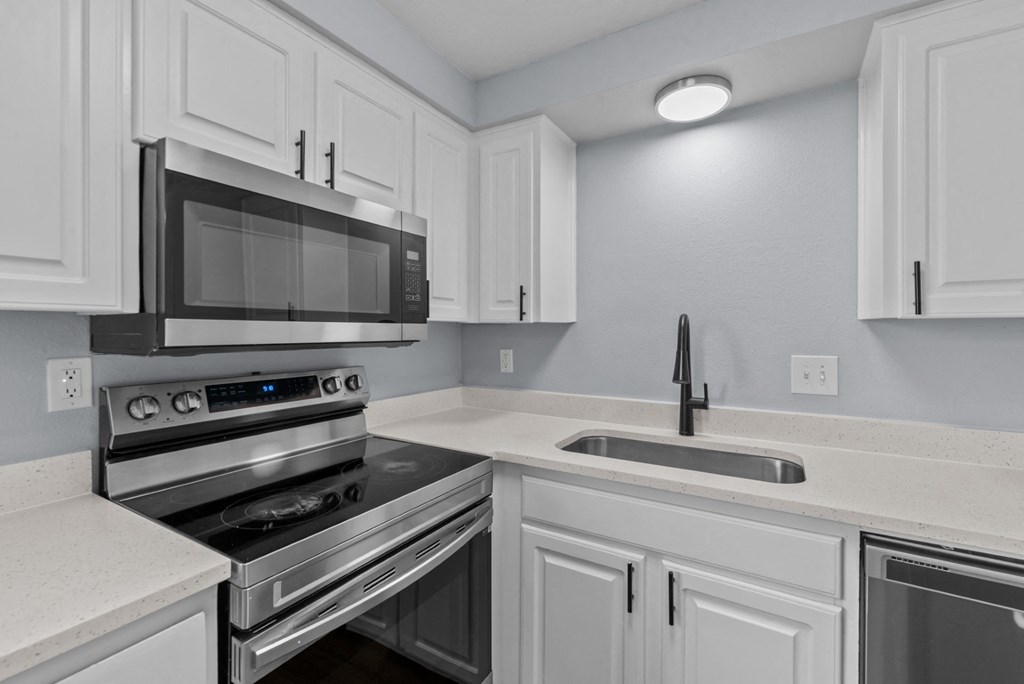 a kitchen with white cabinets and stainless steel appliances