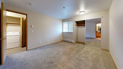 A spacious room with a carpeted floor and a small window.
