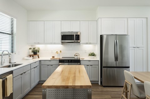 A modern kitchen with a wooden table and stainless steel appliances.