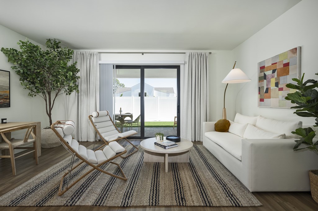 A modern living room with a white sofa, a wooden rocking chair, and a coffee table.