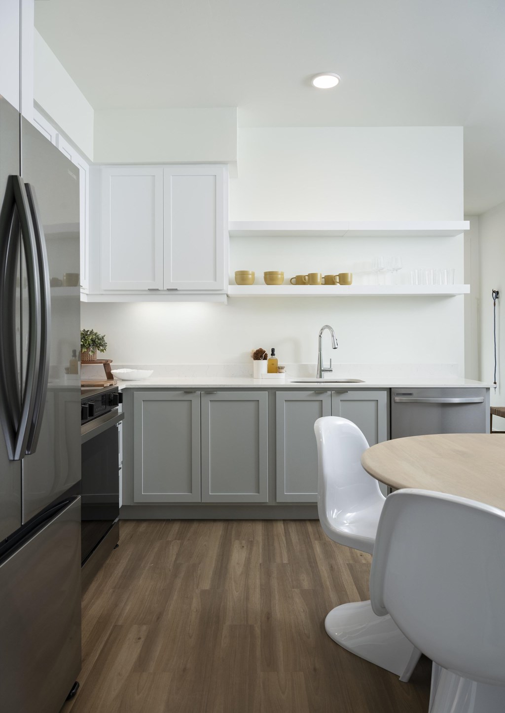 A modern kitchen with a wooden floor and white cabinets.