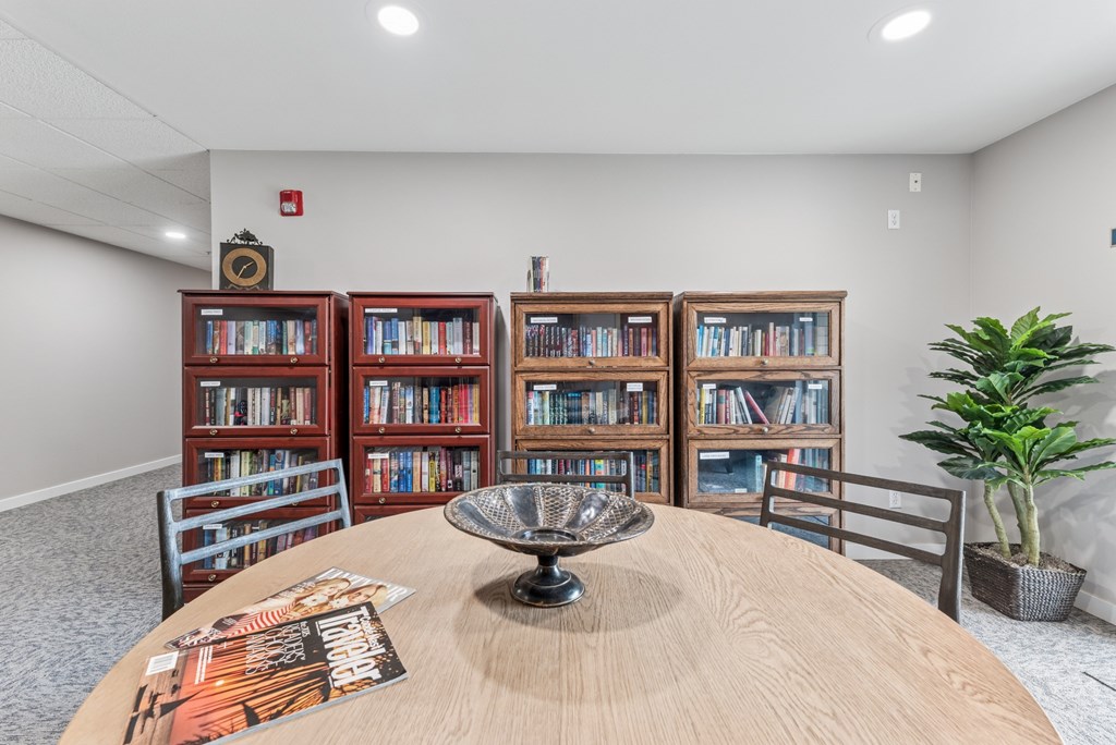 A room with a round table, a bookshelf, and a plant.