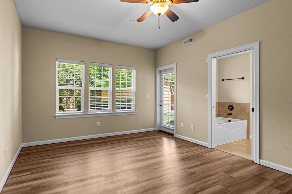 Little Tuscany Apartments & Townhomes - Bedroom with Bathroom, vinyl wood plank flooring, white woodwork, ceiling fan, natural light