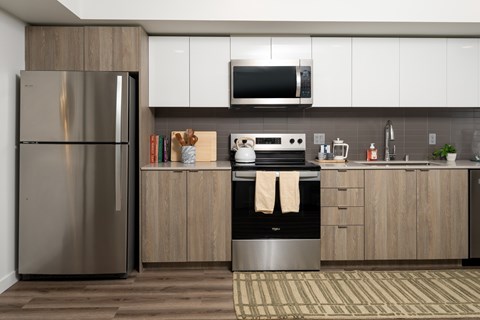 A modern kitchen with a stainless steel refrigerator and wooden cabinets.