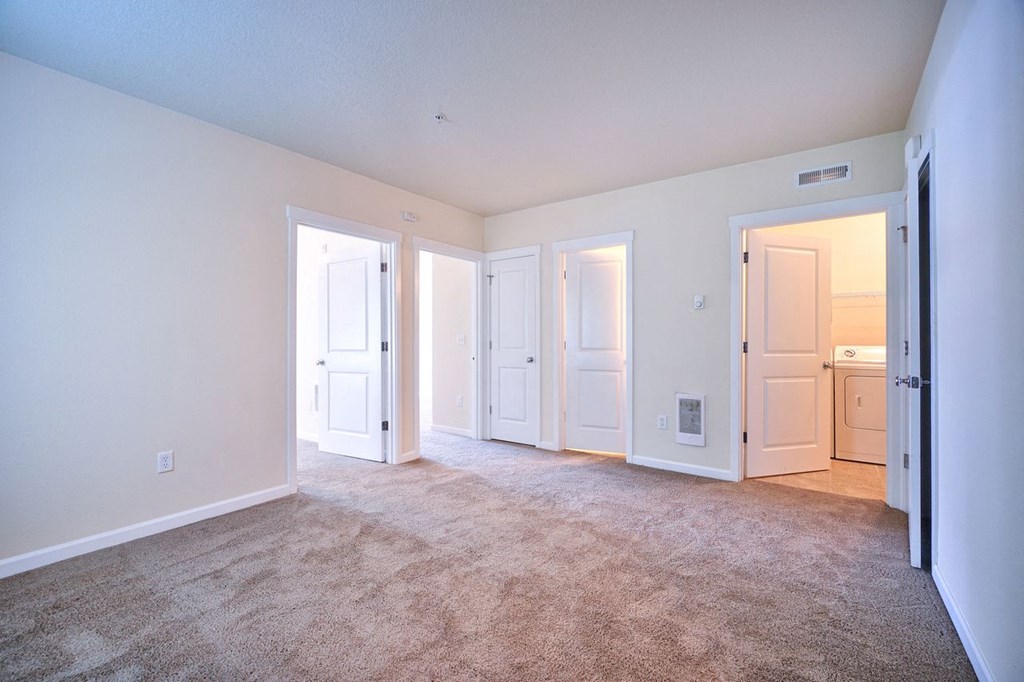 an empty living room with white doors and carpeting