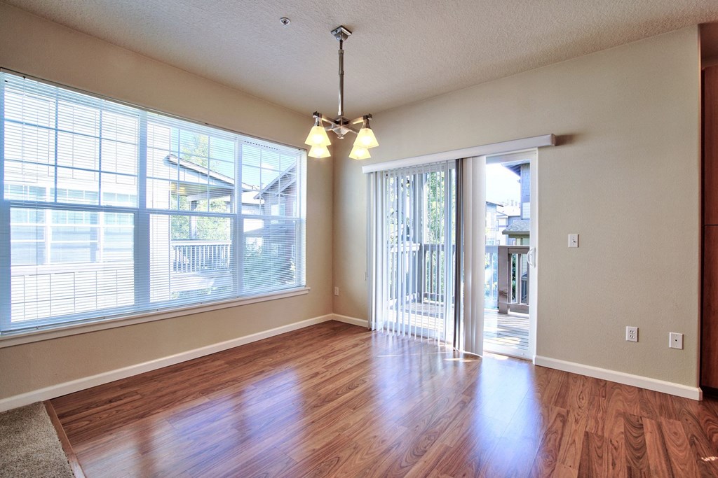 an empty living room with wood floors and large windows