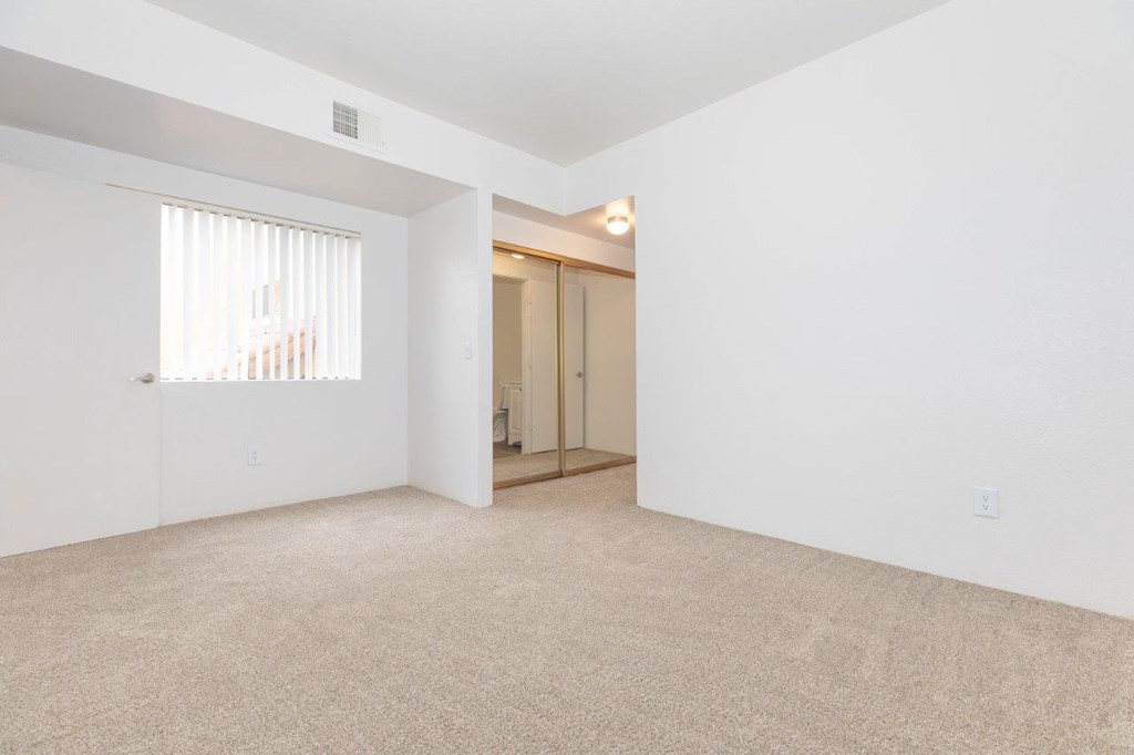 A room with a carpeted floor and a doorway leading to another room.