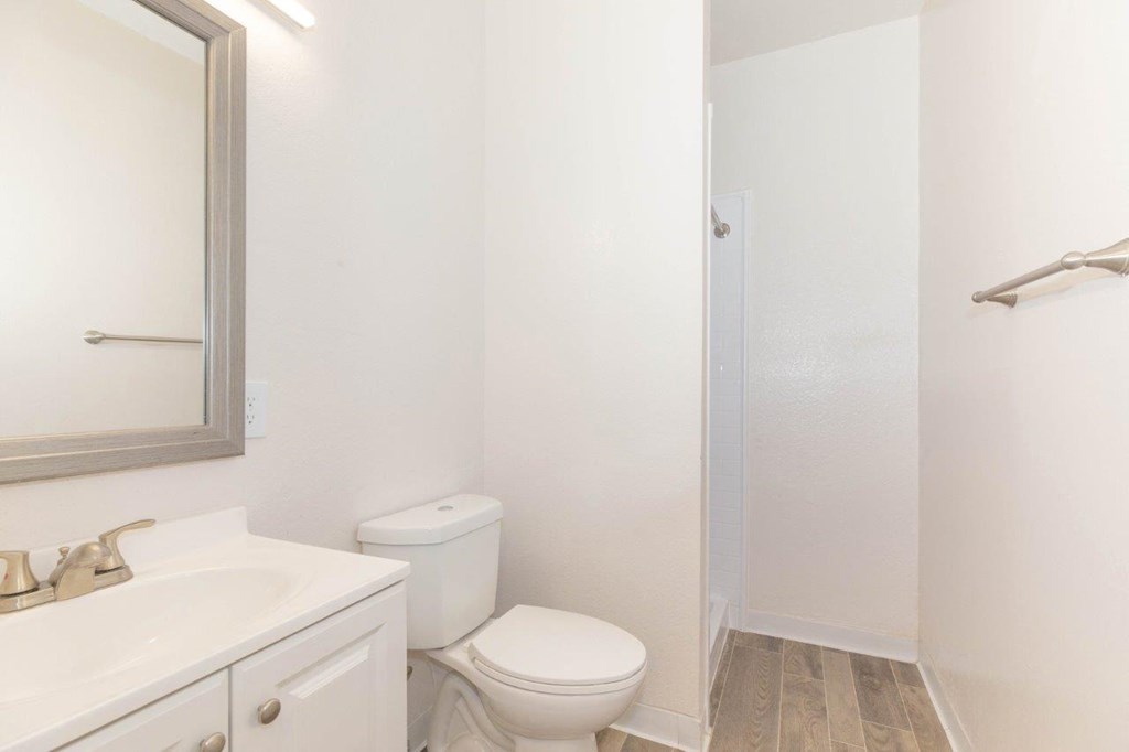 A white bathroom with a toilet, sink, and mirror.