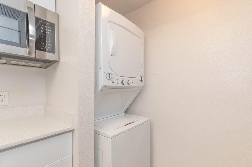 A white dryer is mounted on a wall next to a microwave.