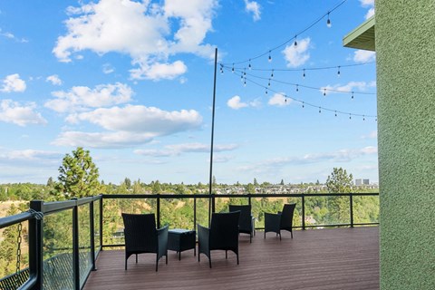 A balcony with chairs and a table overlooking a landscape.