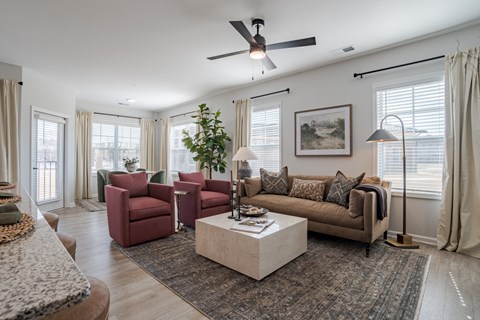 A living room with a red chair and a brown couch.