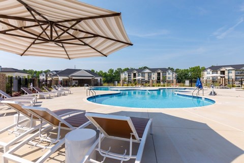 A sunny day at the pool with chairs and umbrellas.