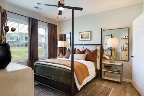 A bedroom with a four poster bed and a mirror on the wall.