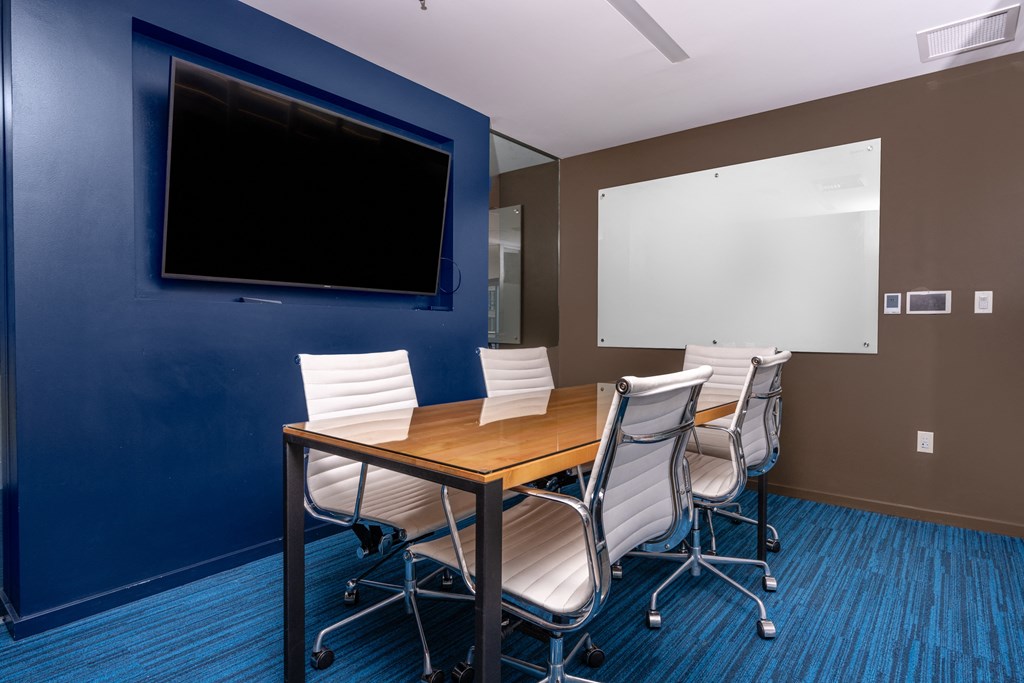 a conference room with a table and chairs and a television