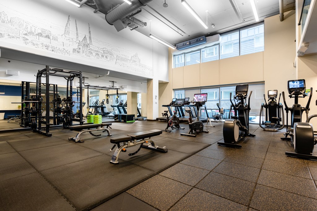 a gym with cardio equipment and weights on a tiled floor