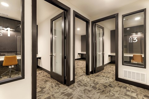 A hallway with black doors and carpeted floors.