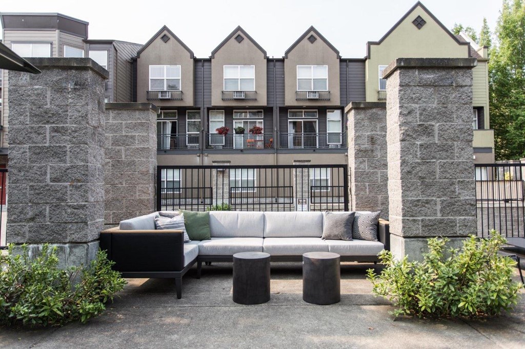a couch and tables in a courtyard in front of an apartment building