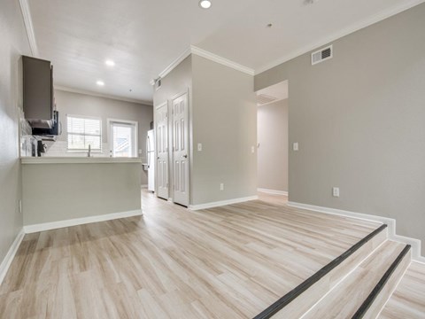 A spacious room with light wood flooring and white walls.