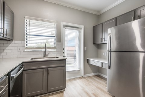 A kitchen with a stainless steel refrigerator and wooden floors.