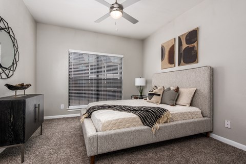A bedroom with a bed, a dresser, and a ceiling fan.