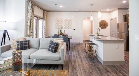 A modern living room with a grey sofa and a wooden floor.
