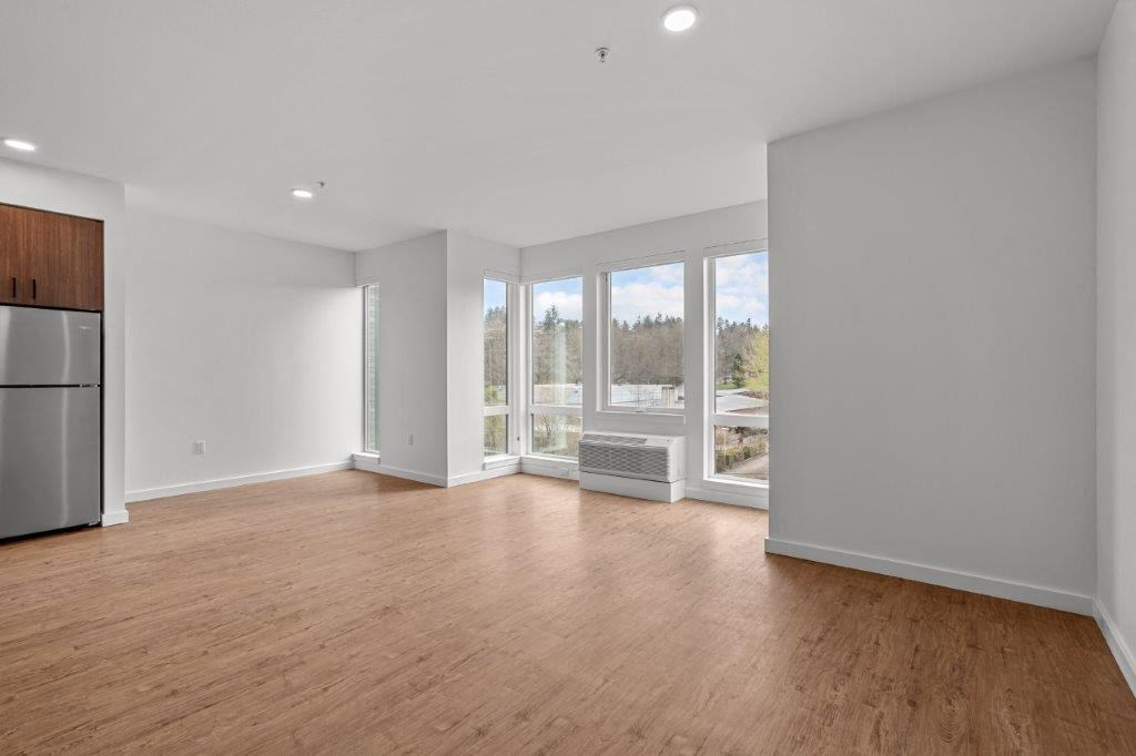 an empty living room with wood floors and a large window