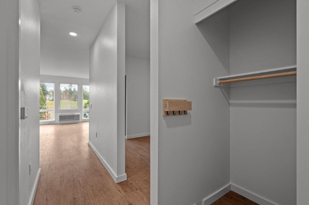 a living room with a wooden floor and a hallway with a window