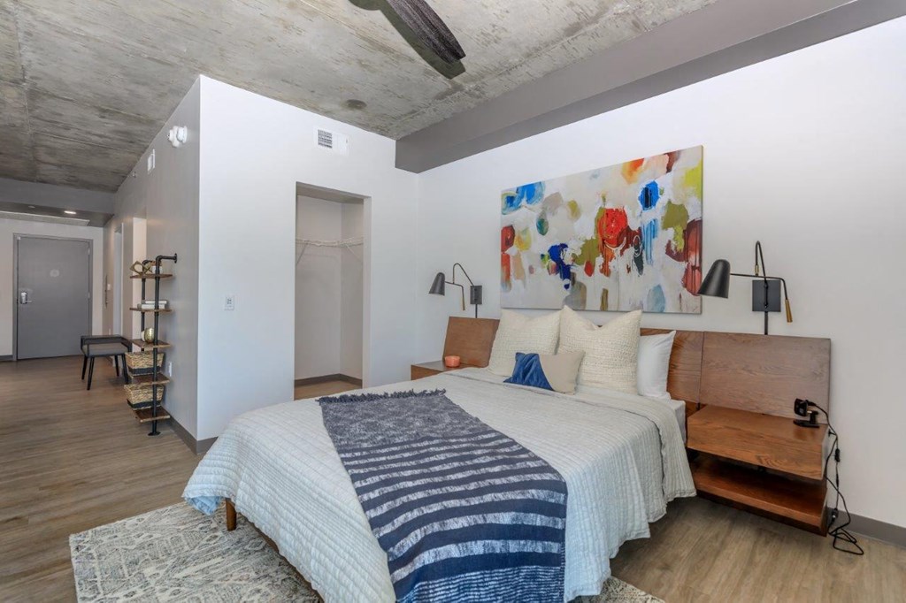 A bedroom with a bed, a bench, and a painting on the wall.