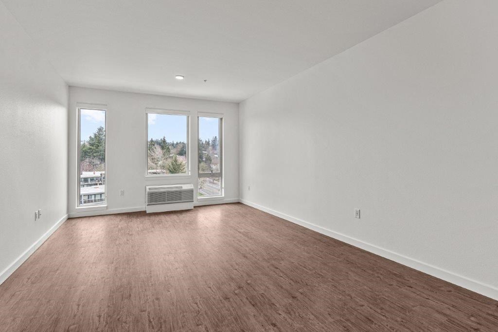 an empty living room with wood flooring and a window
