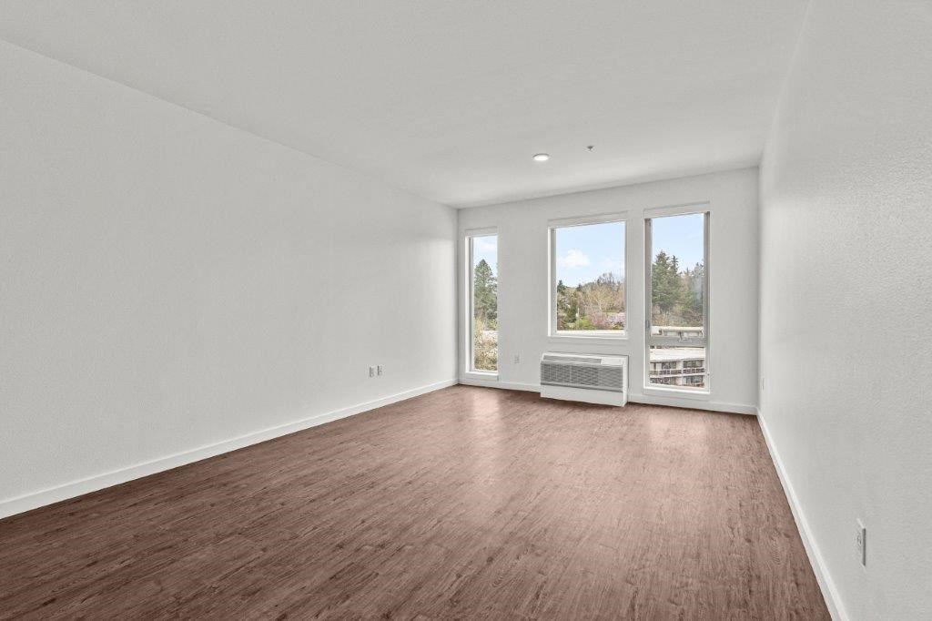 an empty living room with wood floors and a window