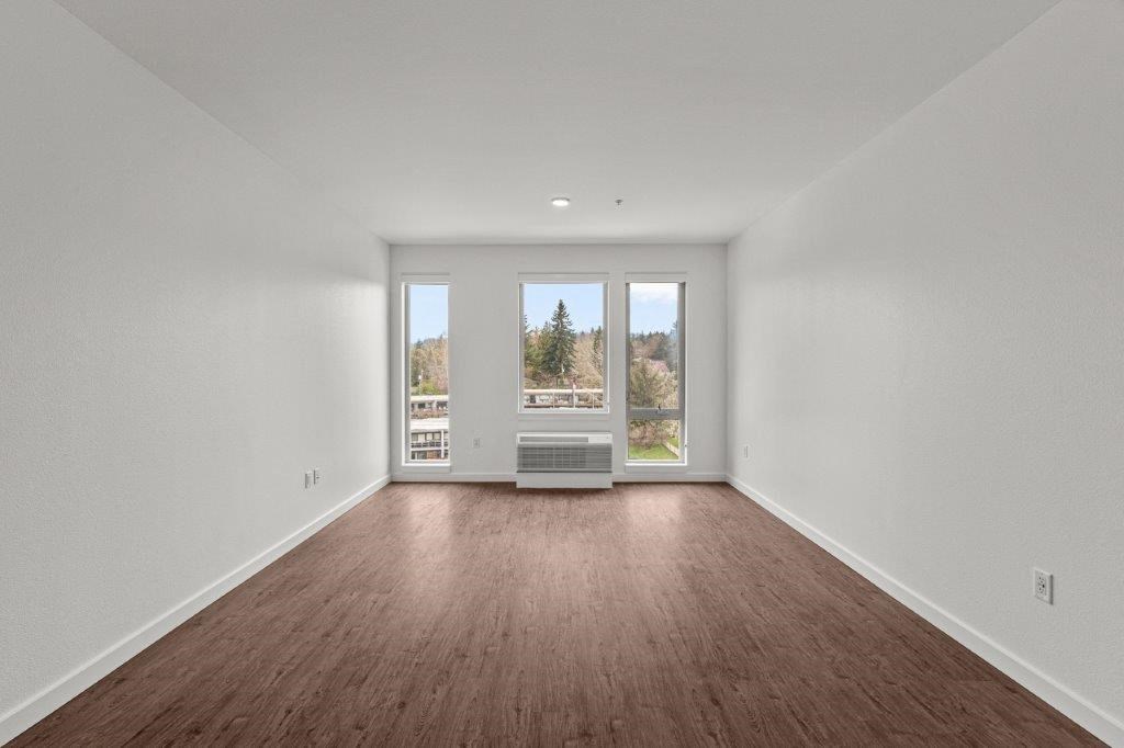 an empty living room with wood floors and a window