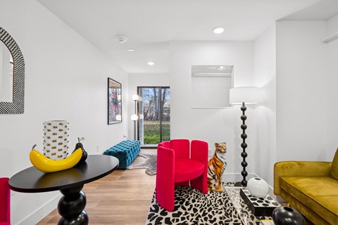 A living room with a yellow couch, a red chair, and a black table with a banana on it.