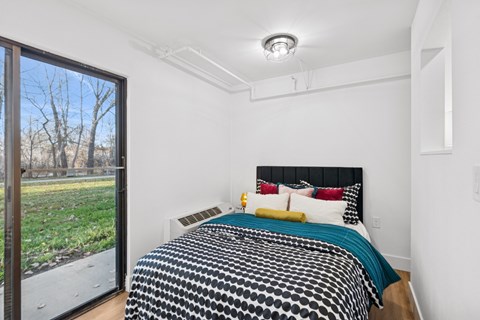 A bedroom with a bed and a window overlooking a field.
