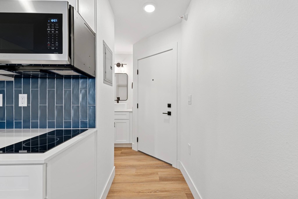 A kitchen with a blue backsplash and white cabinets.