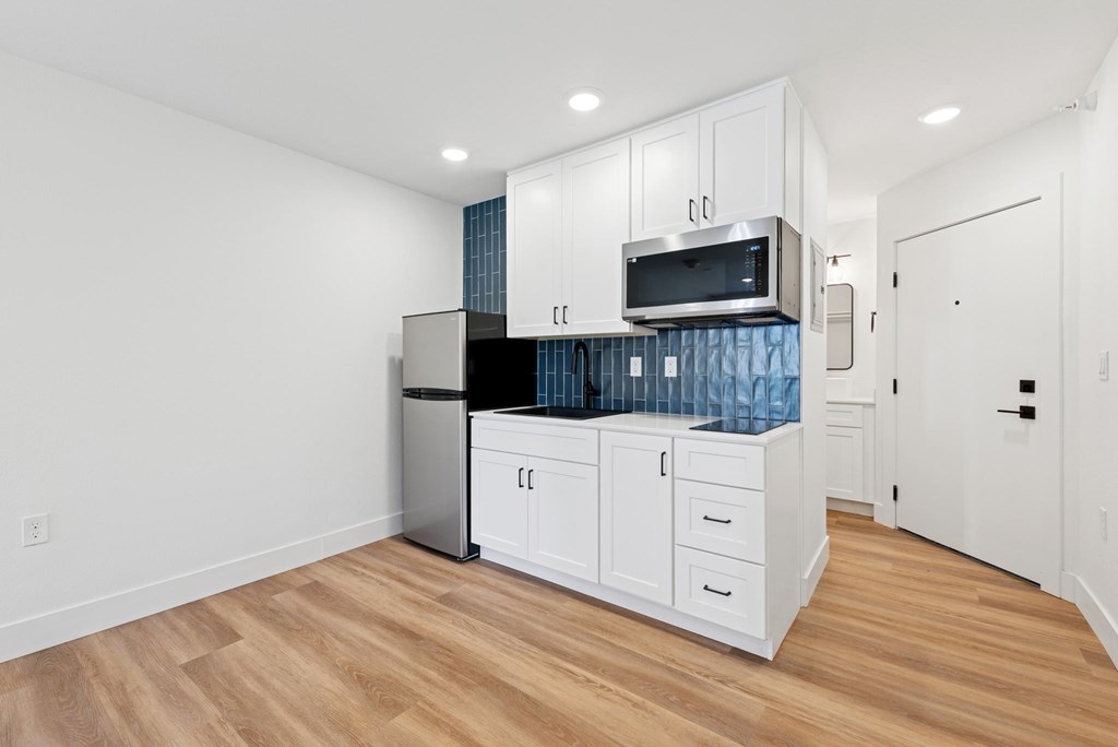 A kitchen with white cabinets and a stainless steel refrigerator.
