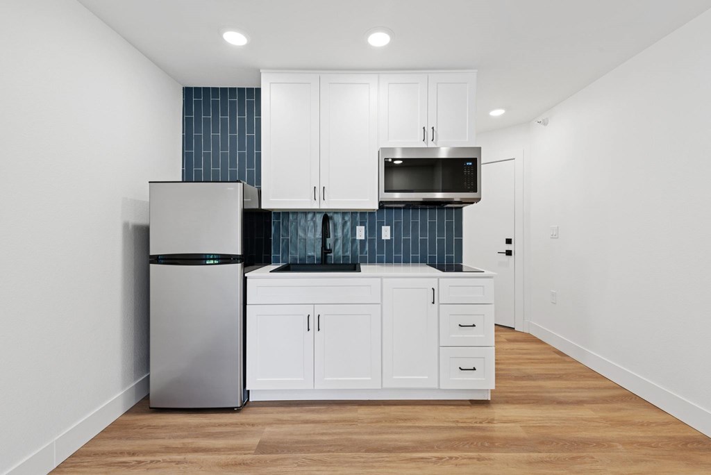 A kitchen with white cabinets and a stainless steel refrigerator.