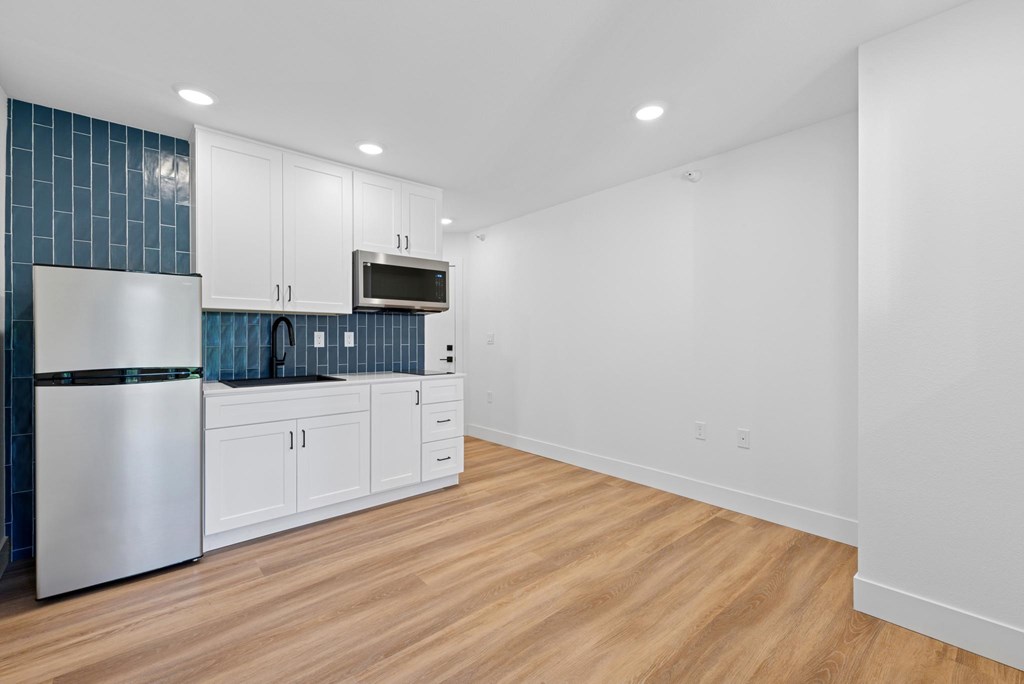 A kitchen with white cabinets and a stainless steel refrigerator.