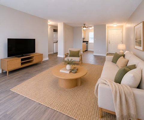 A living room with a white couch, a wooden coffee table, and a flat-screen TV.