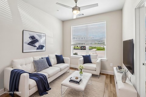 A living room with a white couch and a ceiling fan.