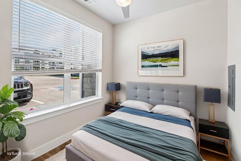 A bedroom with a bed, nightstand, and a painting on the wall.