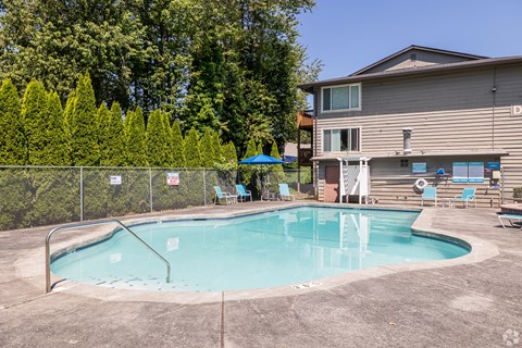 A small pool surrounded by a fence and trees.