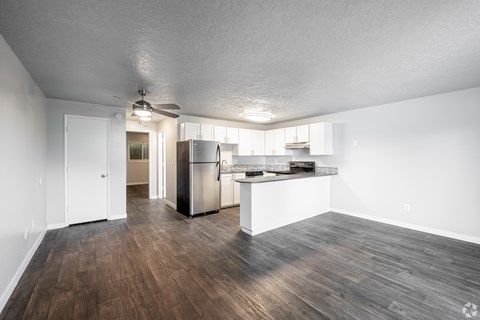 A kitchen with white walls and a wooden floor.