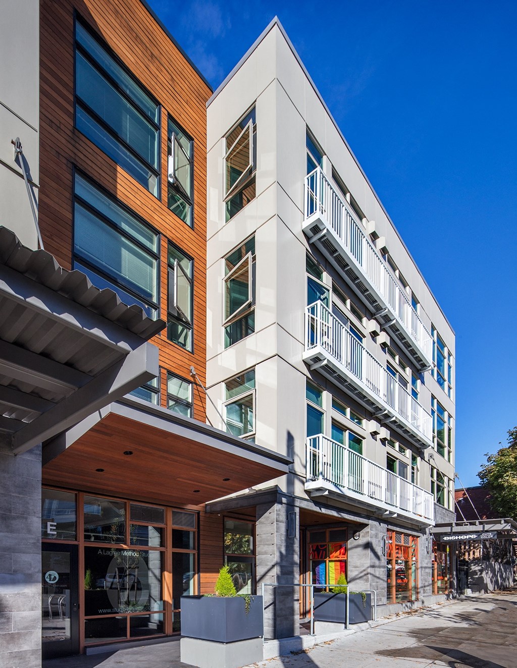 a view of the side of a building with balconies and a sidewalk